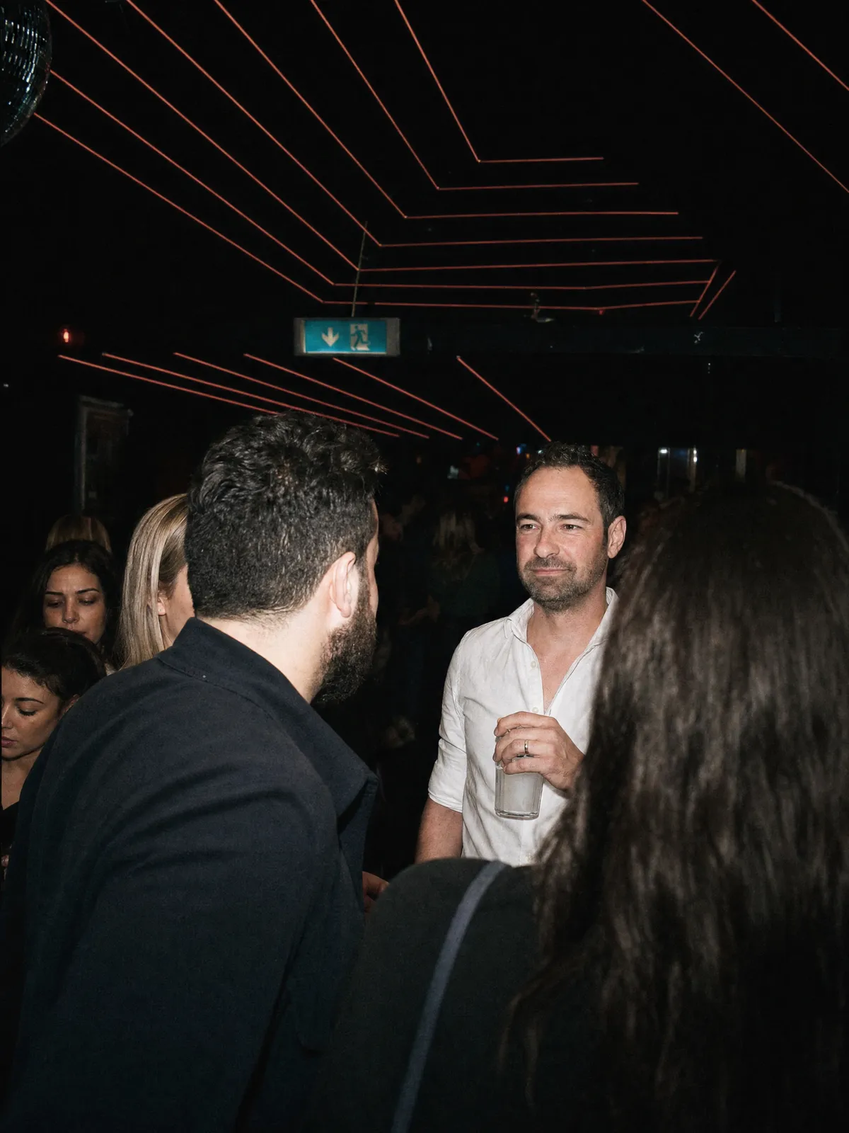 Gast mit Drink unter den Lichtlinien der Decke